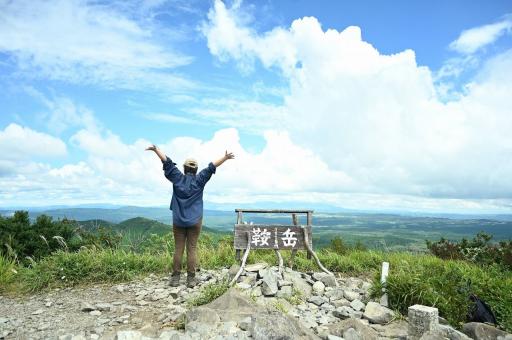 写真：鞍岳の頂上で腕を広げて景色を楽しむ女性