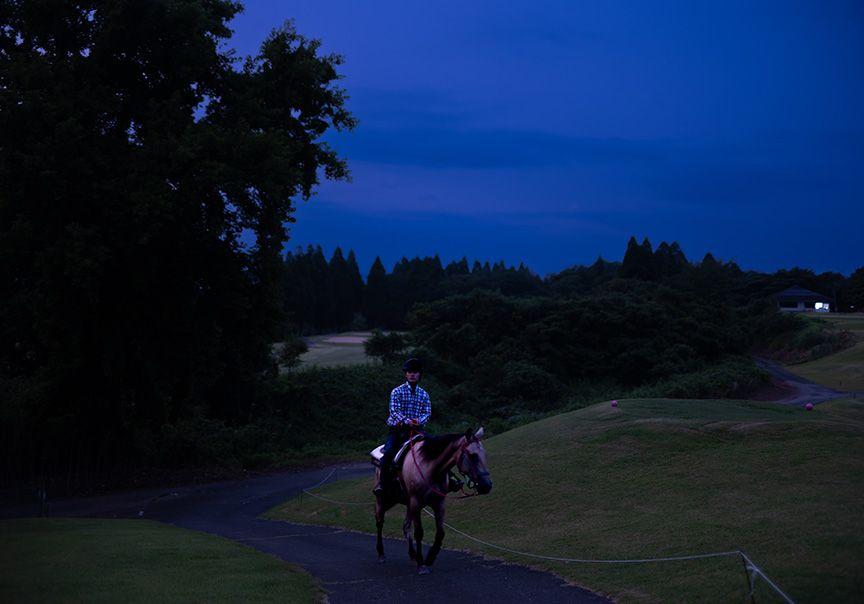 ゴルフ場を馬で歩く様子の写真