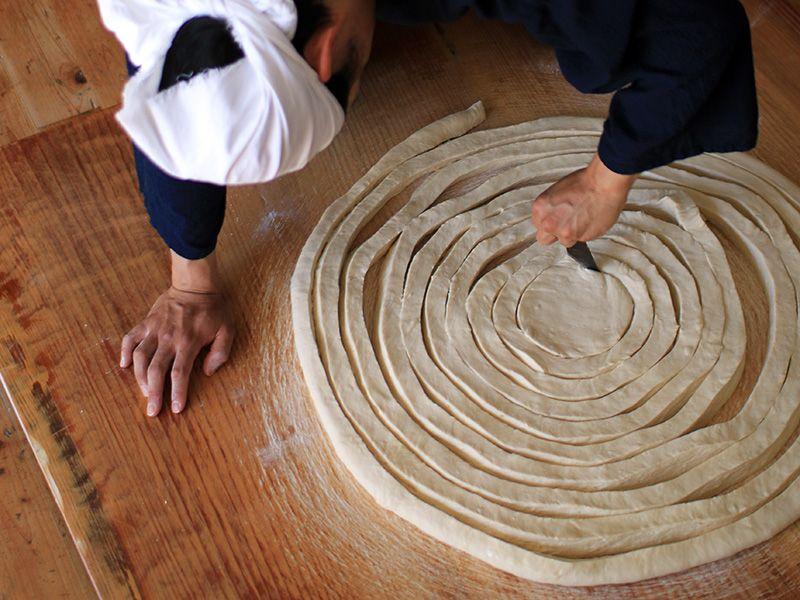 写真：素麺づくりの工程。円形に延ばした生地を渦巻き状に切っている様子