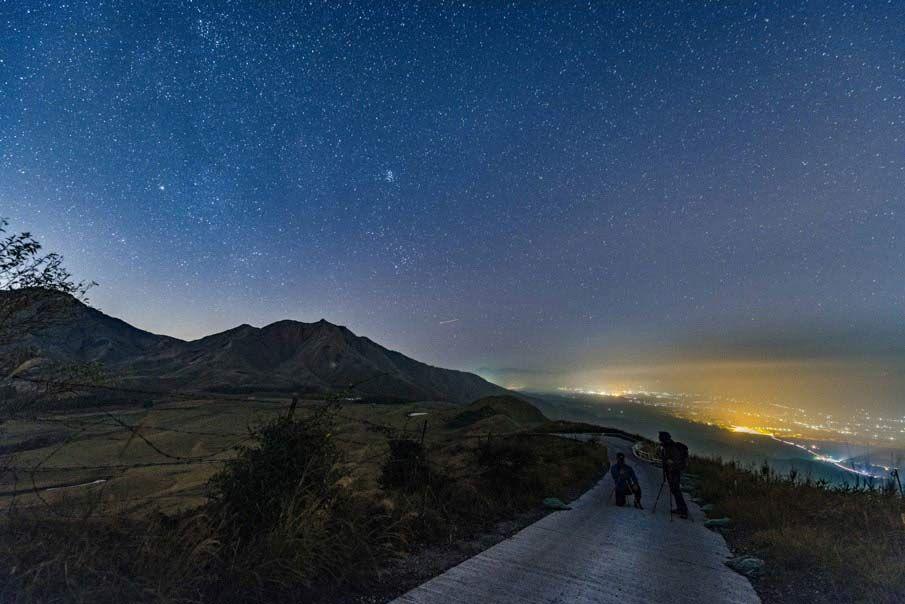 夜の阿蘇の景色。満天の星空と街の夜景が見える写真