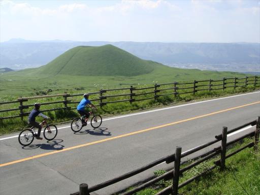 写真：阿蘇山と男性のサイクリング姿