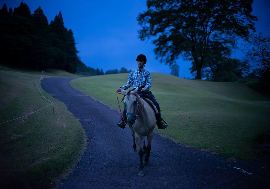 馬で夜のゴルフ場の坂道を下る様子の写