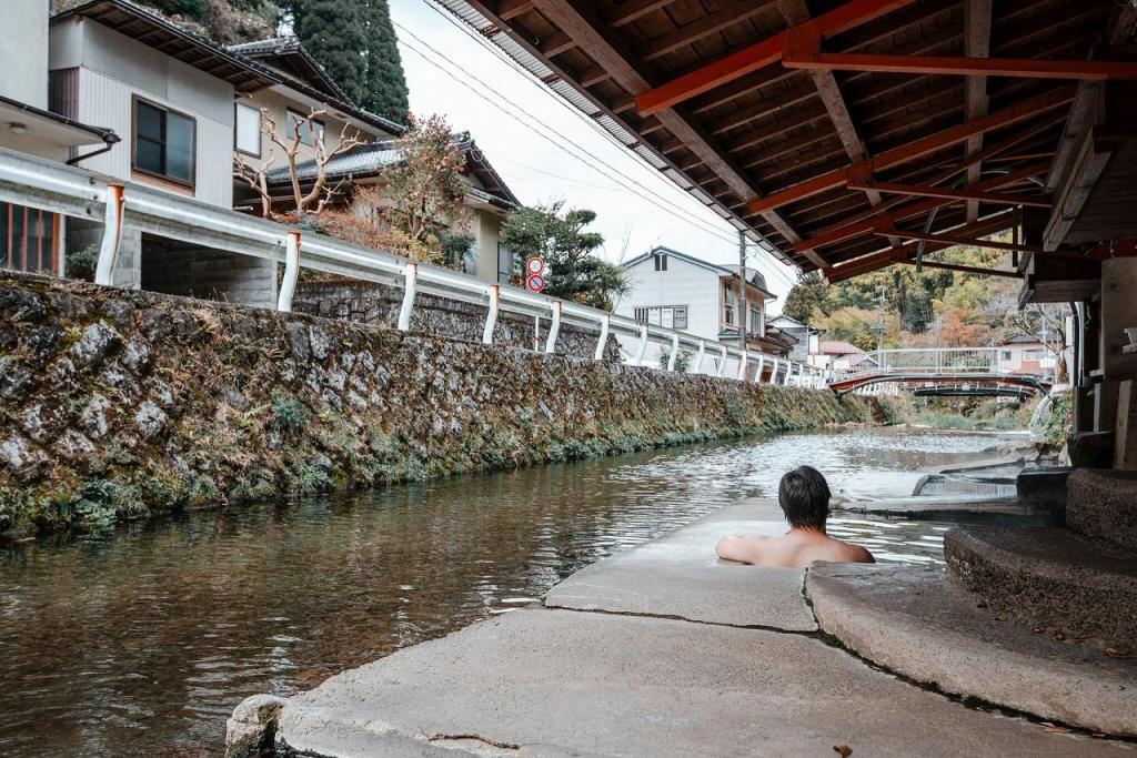 写真：川湯に入浴している男性の背中