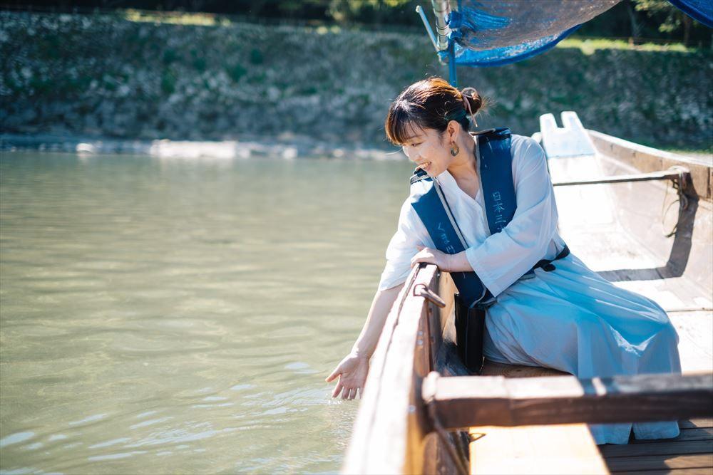 写真：木舟の上から球磨川に手を伸ばす女性