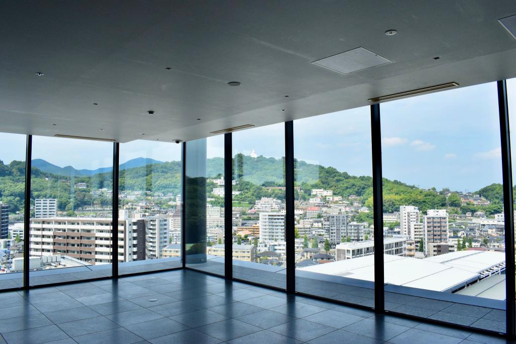 店舗入り口から望むことができる、熊本駅周辺の街並みや駅周辺の山々（花岡山）の写真