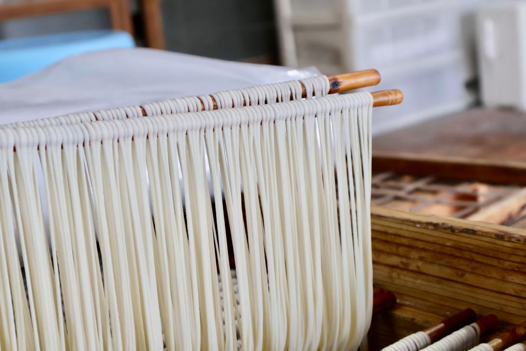 写真：素麺づくりの工程。細く延ばした生地が竹棒にかけられている様子