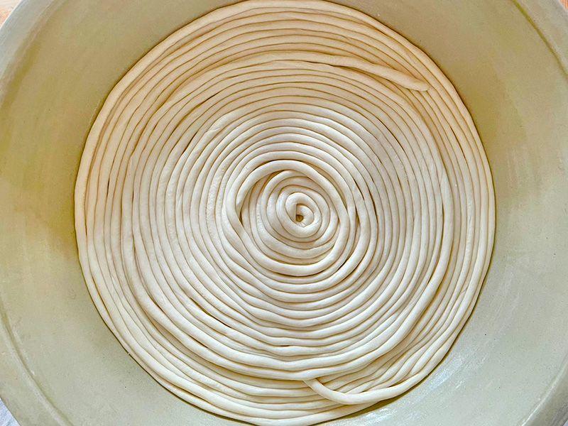 写真：素麺づくりの工程。ひも状に延ばした生地を渦巻き状に巻いて置いている様子