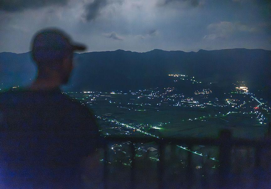 高台から南阿蘇の街の夜景をながめる写真