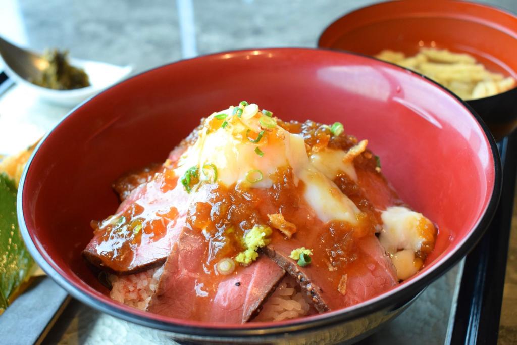 あか牛丼の上に、温泉卵とネギ、わさびをトッピングした写真