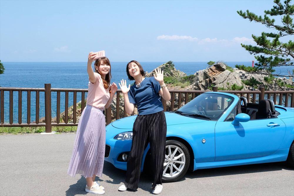 写真：車をバックに写真を撮る女性