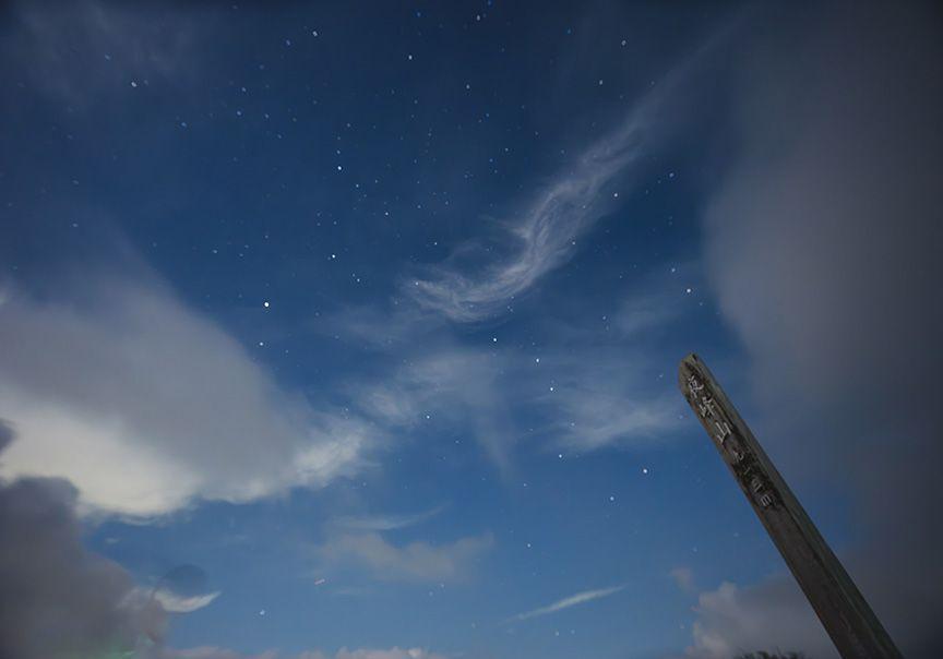 夜峰山の山頂の表示と星空を見上げる写真